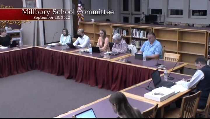 Five people sit at a table for a school committee meeting.