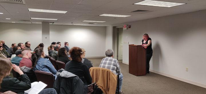 A woman at a podium in front of a crowd.